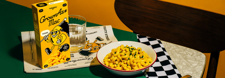 Table setting with a bowl of mac and cheese next to a box of GrownAs Foods.